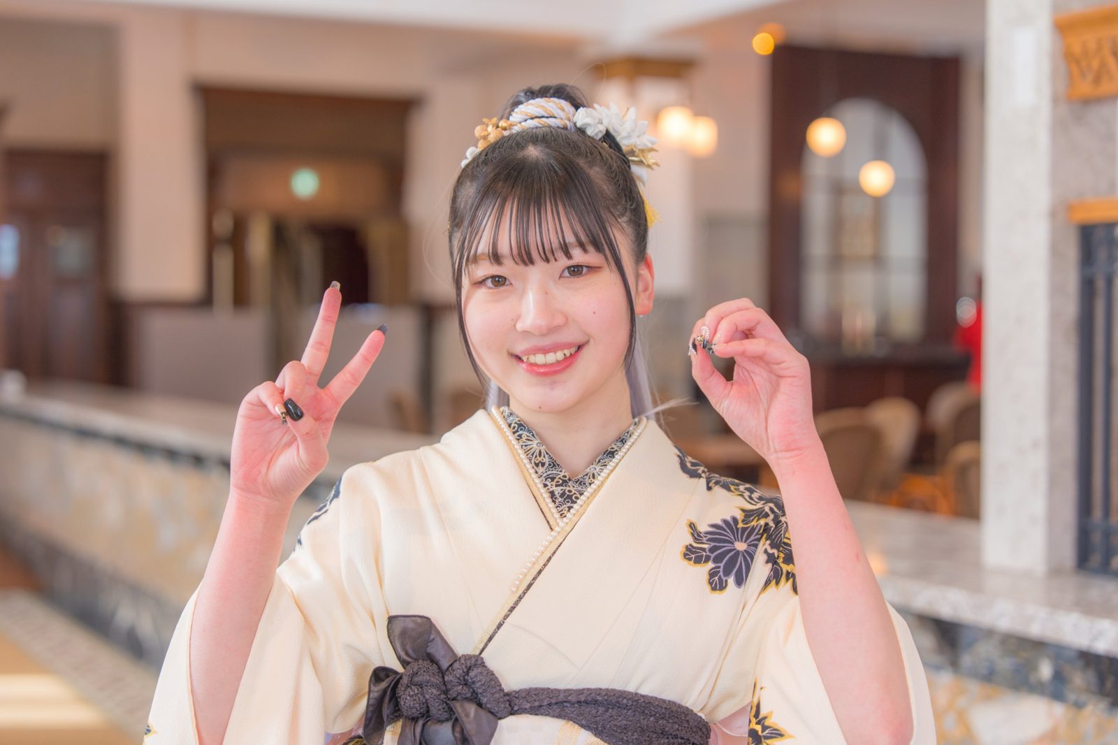 振袖姿でピースをする笑顔の女性