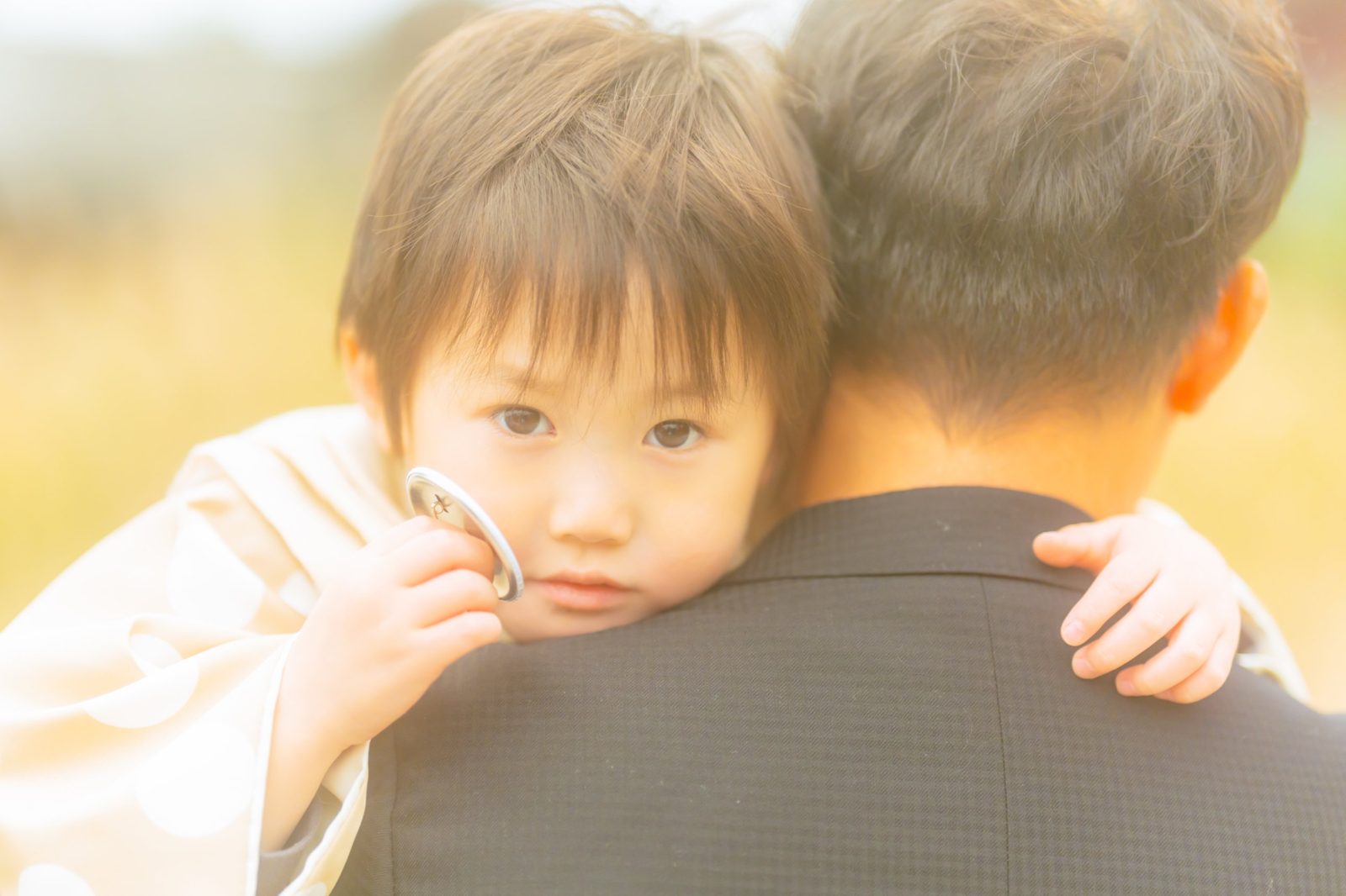 お父さんの肩に抱かれて、こちらを見つめる小さな男の子