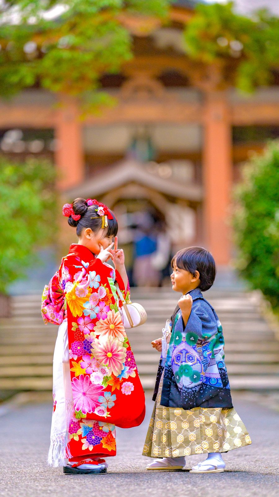 お寺の前でポーズをとる姉と、見上げる弟