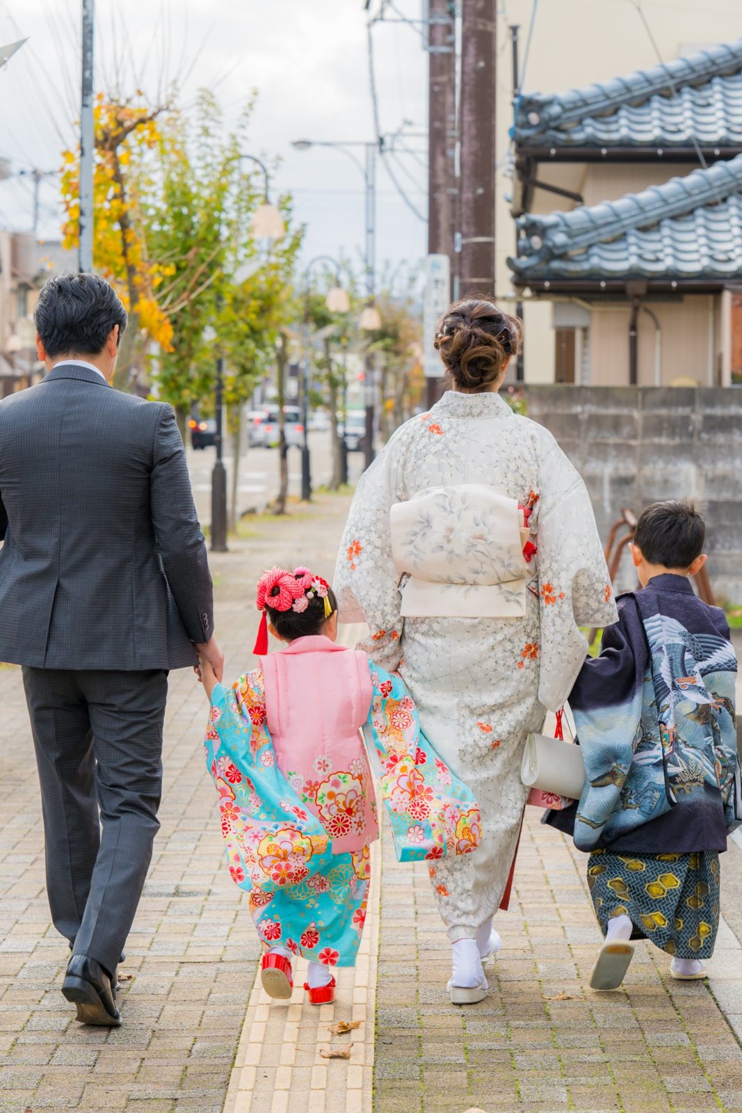 手をつないで歩く家族の後ろ姿