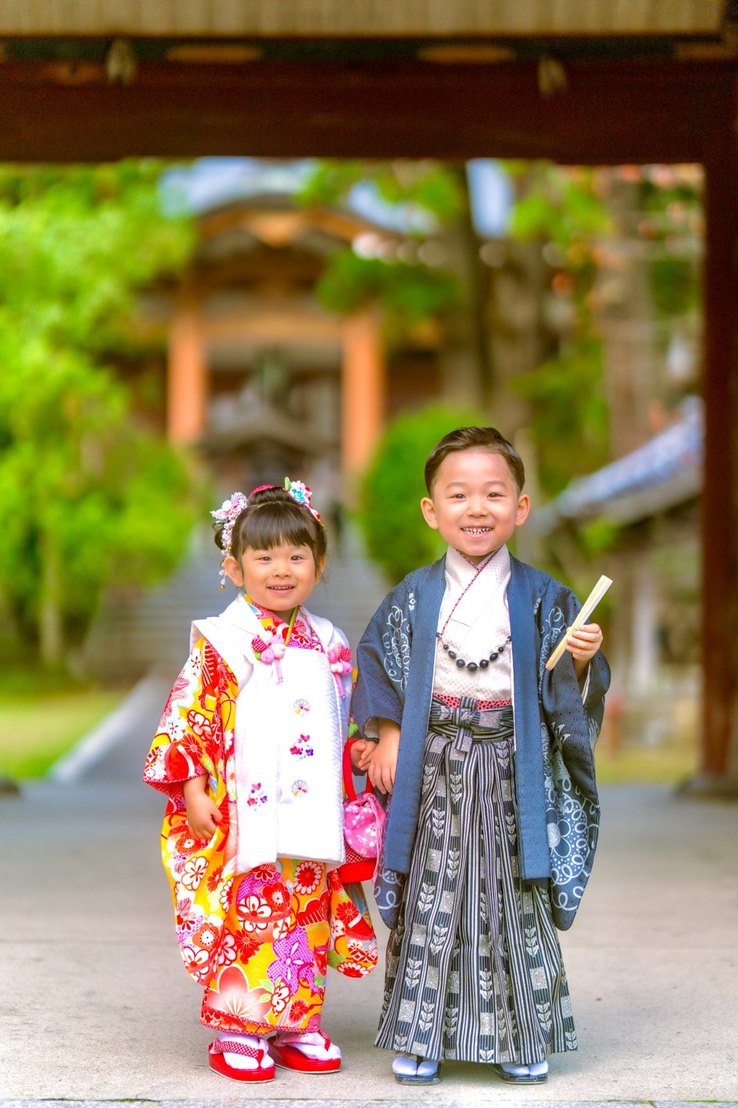 門の下でにっこり並ぶ、着物姿の兄妹