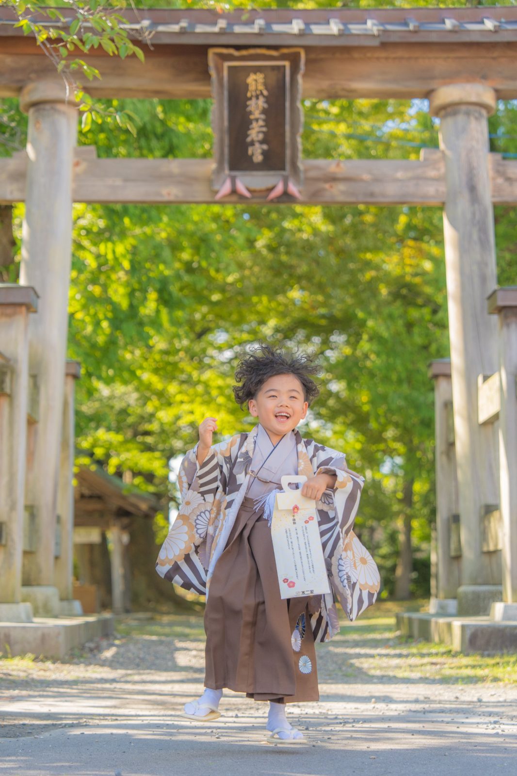鳥居の前を笑顔で駆けてくる袴姿の男の子