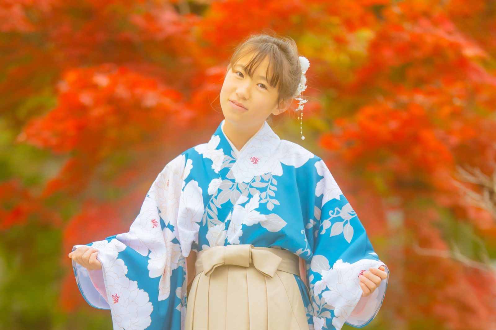 紅葉を背に、袴姿でほほえむ女の子