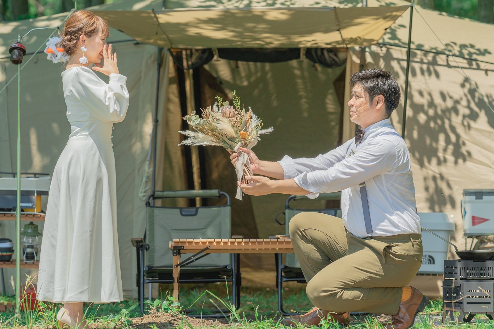 キャンプ場で、ひざまずいてブーケを差し出す新郎