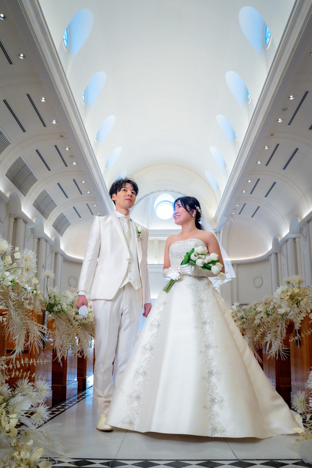 白いチャペルに立つ新郎新婦